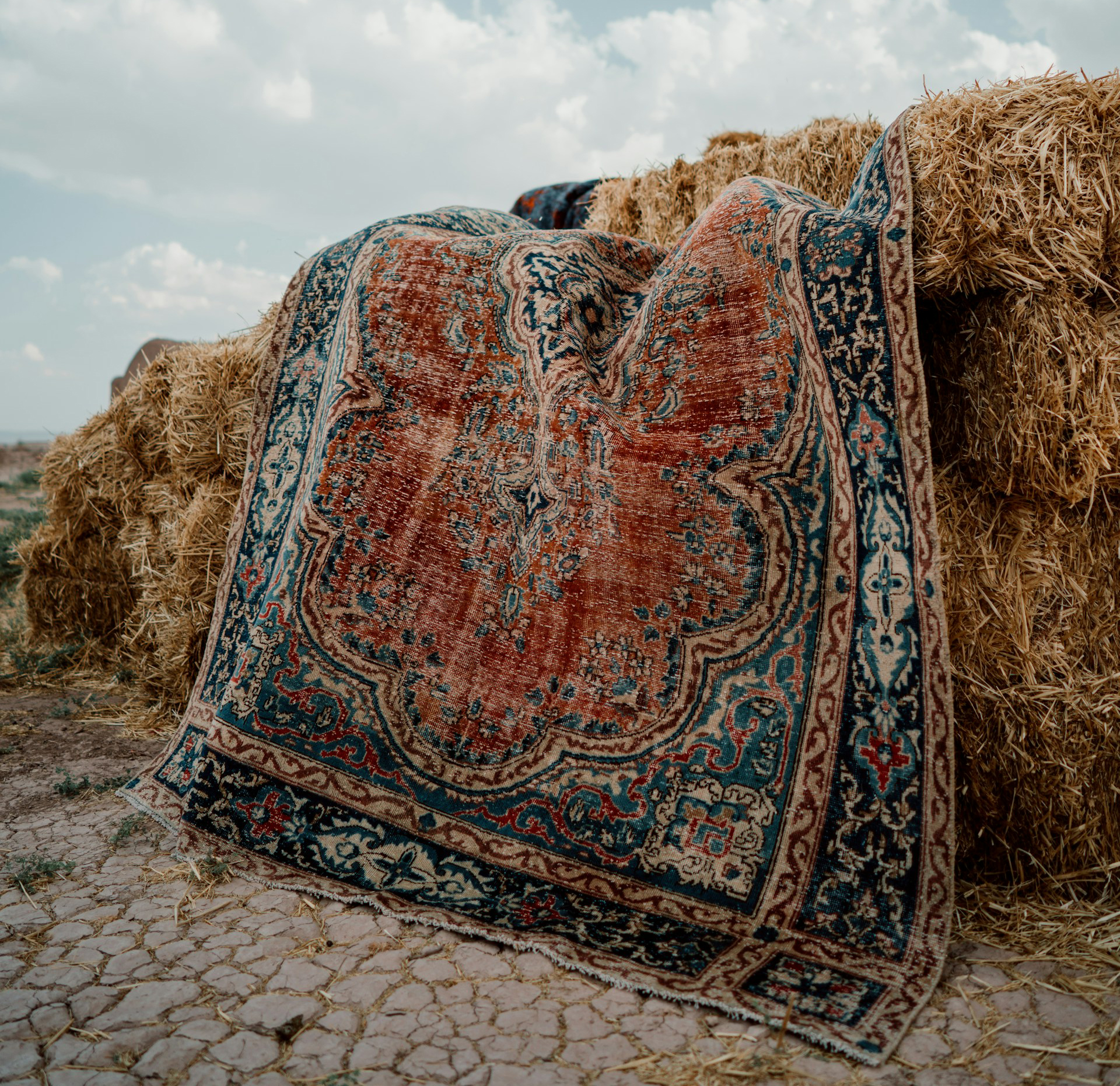 Vintage Turkish rug displayed on uneven ground, highlighting its rich colors and textures