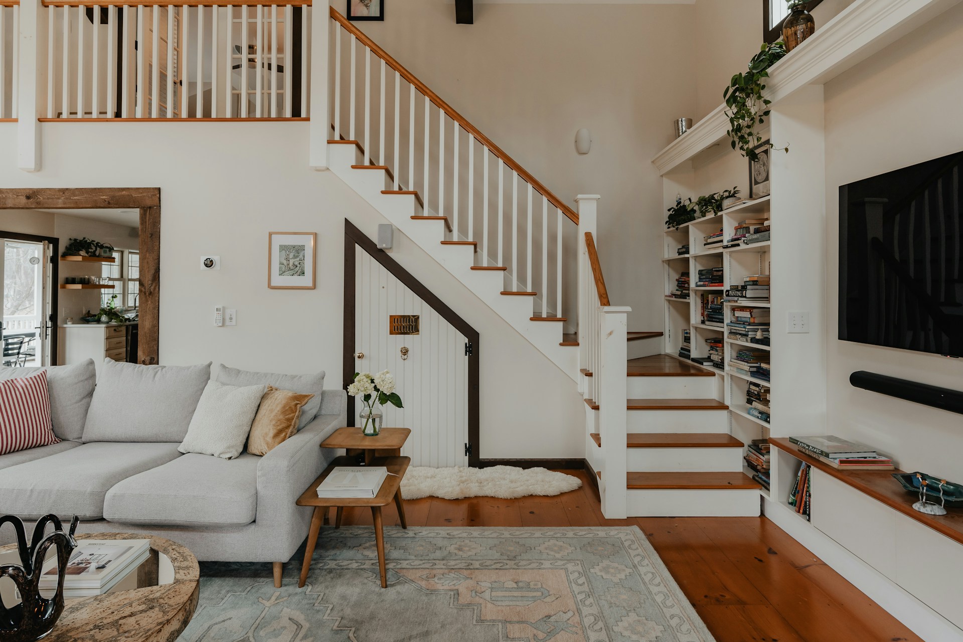 A bright and airy modern living room showcasing a large, intricately patterned handwoven rug in earthy tones, anchoring a minimalist sofa and contemporary decor.