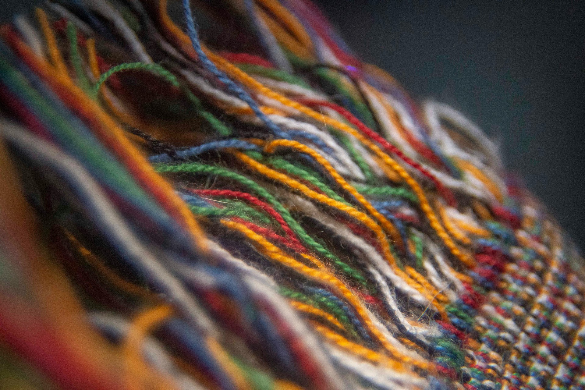 The photograph depicts a hand-woven Moroccan carpet comprising a vibrant assortment of yellow, red, green, blue, and black threads. The knots are discernible, and select areas exhibit non-woven threads.