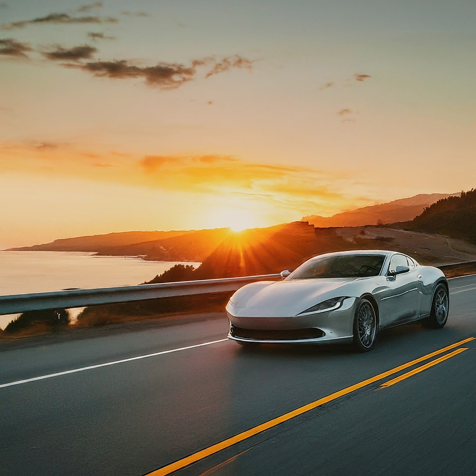 A car is driving on a road with mountains in the background.