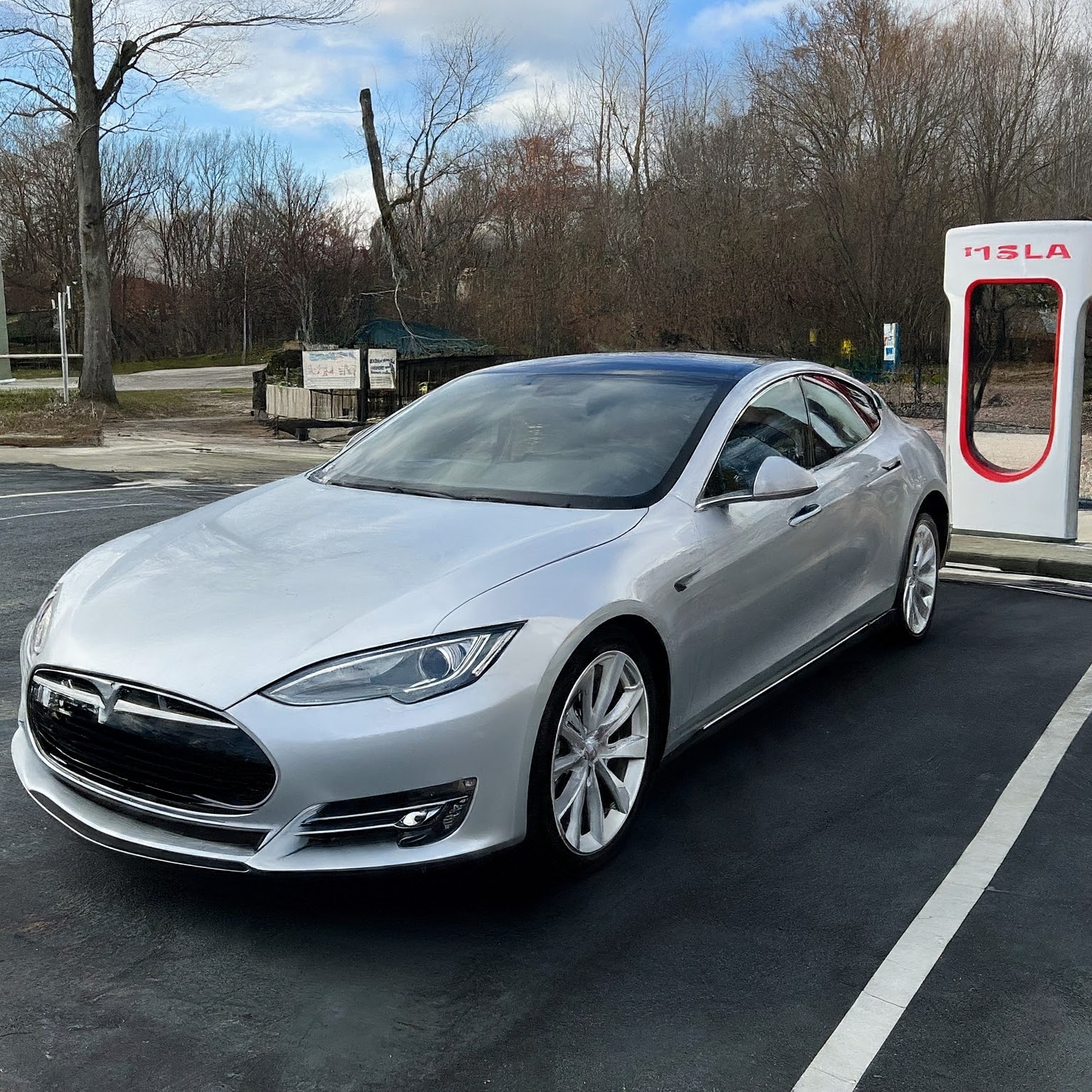 A white car parked in front of a parking meter.