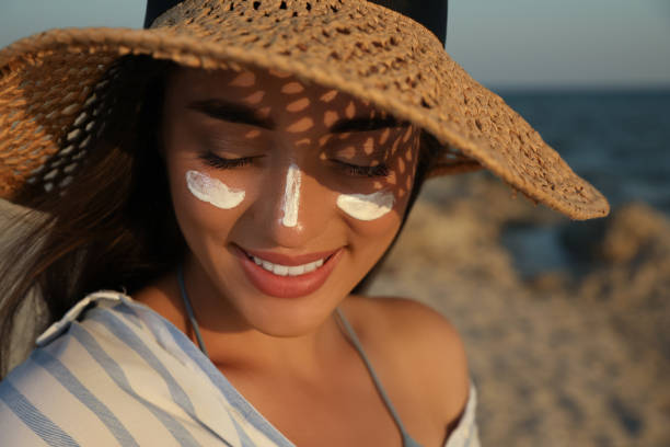 femme à la plage avec un chapeau et une protection solaire sur le visage