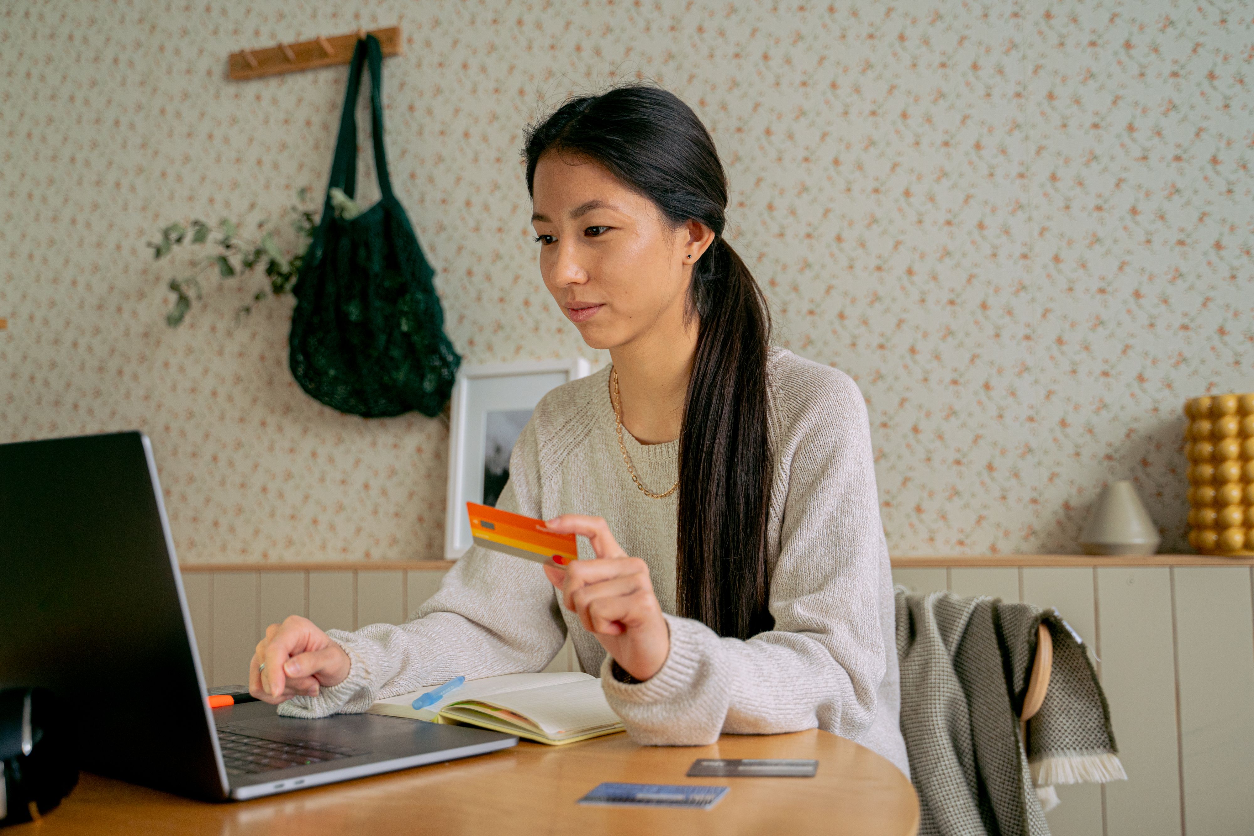 Woman reviewing a credit card and managing finances on a laptop at home