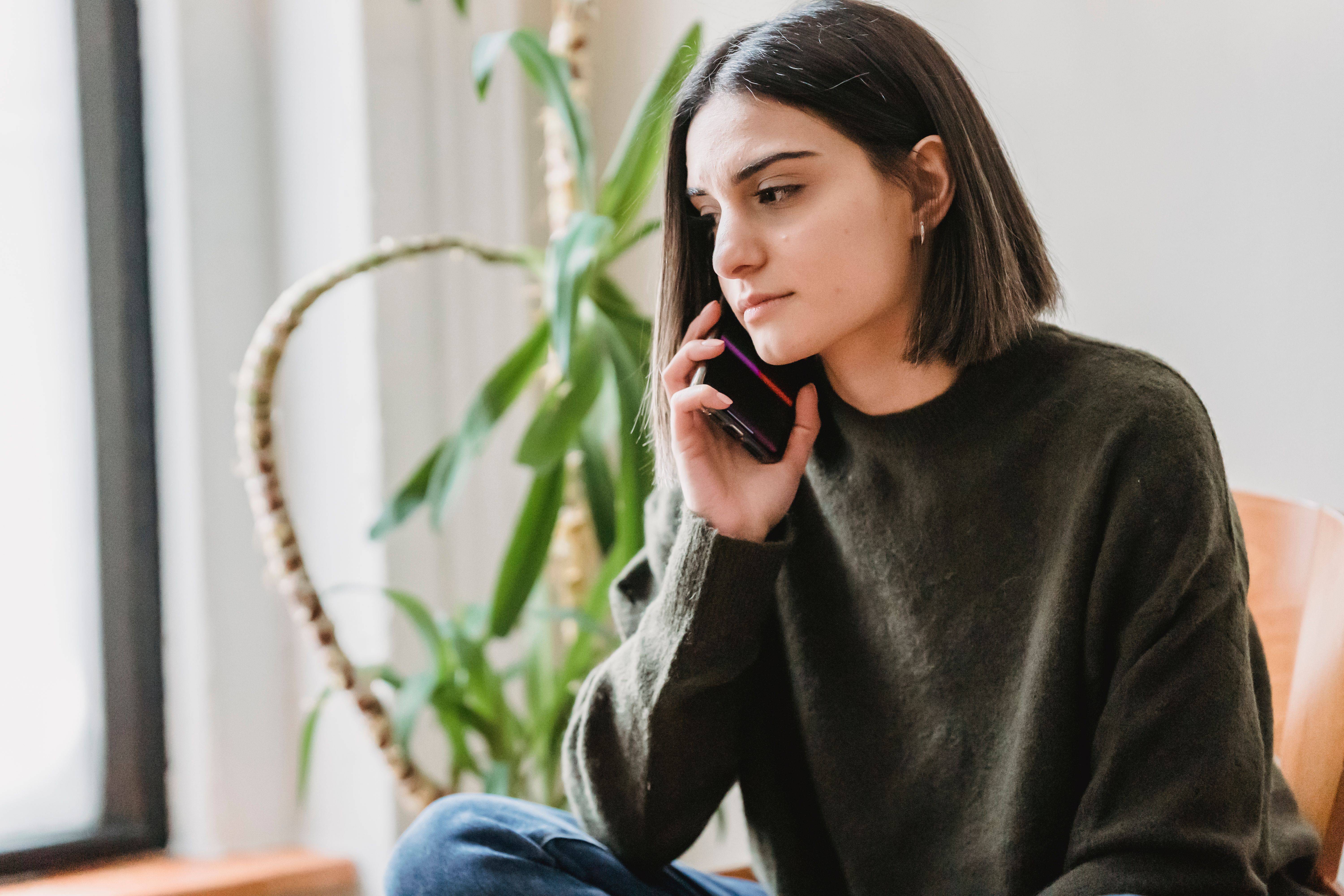 Woman making a phone call while reviewing her variable-income budget at home
