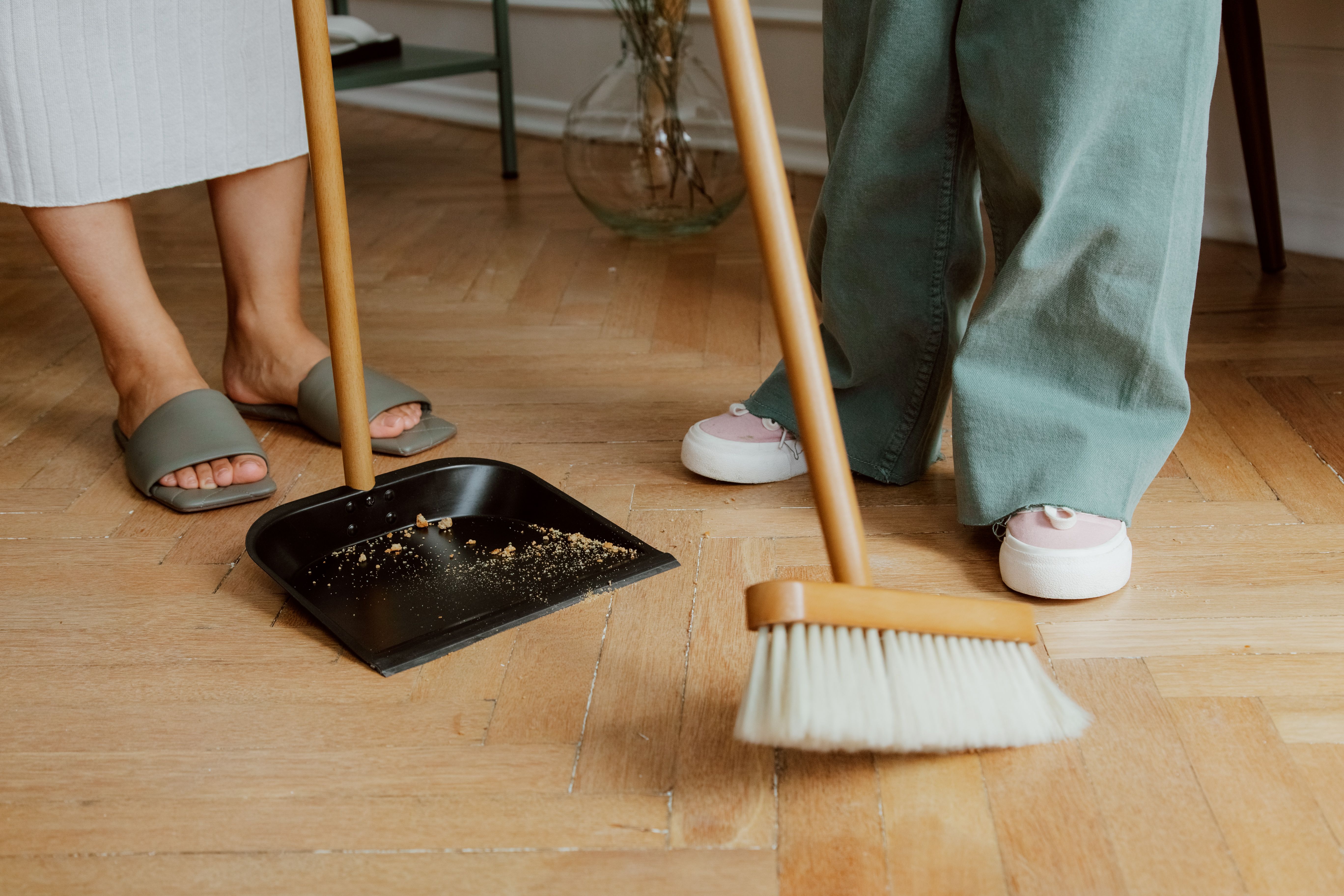 Two people sweeping up wooden floor