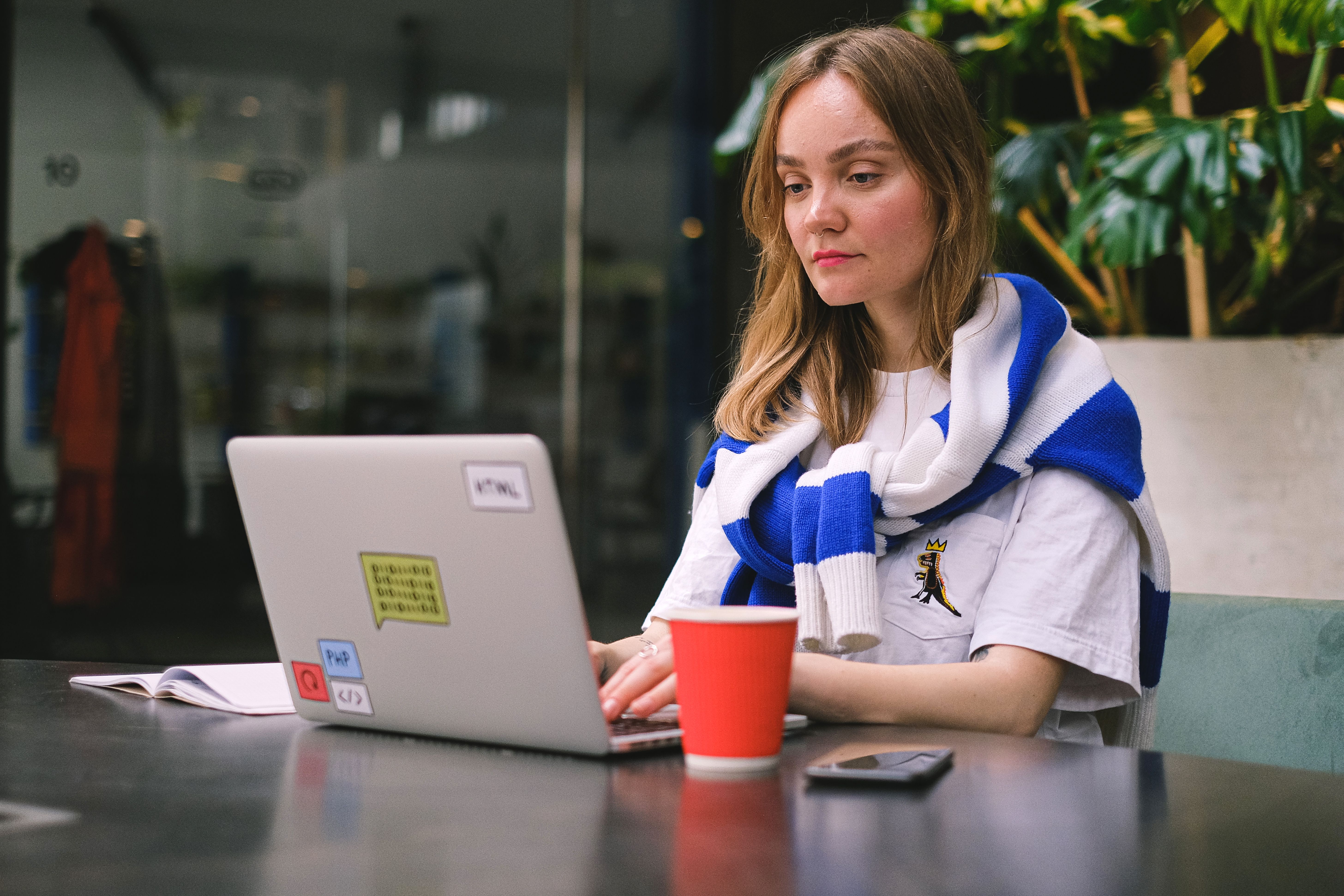 Freelancer working on a laptop in a cafe while managing fluctuating monthly income